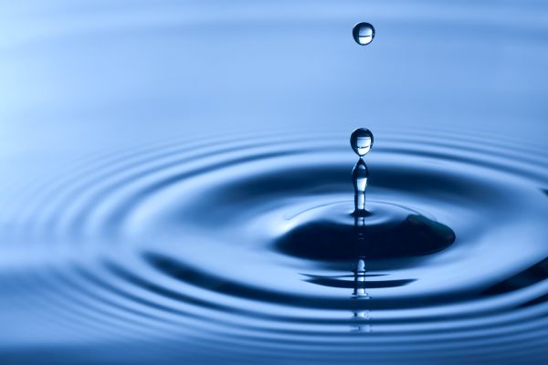 Closeup of a water droplet creating ripples in a dark blue body of water