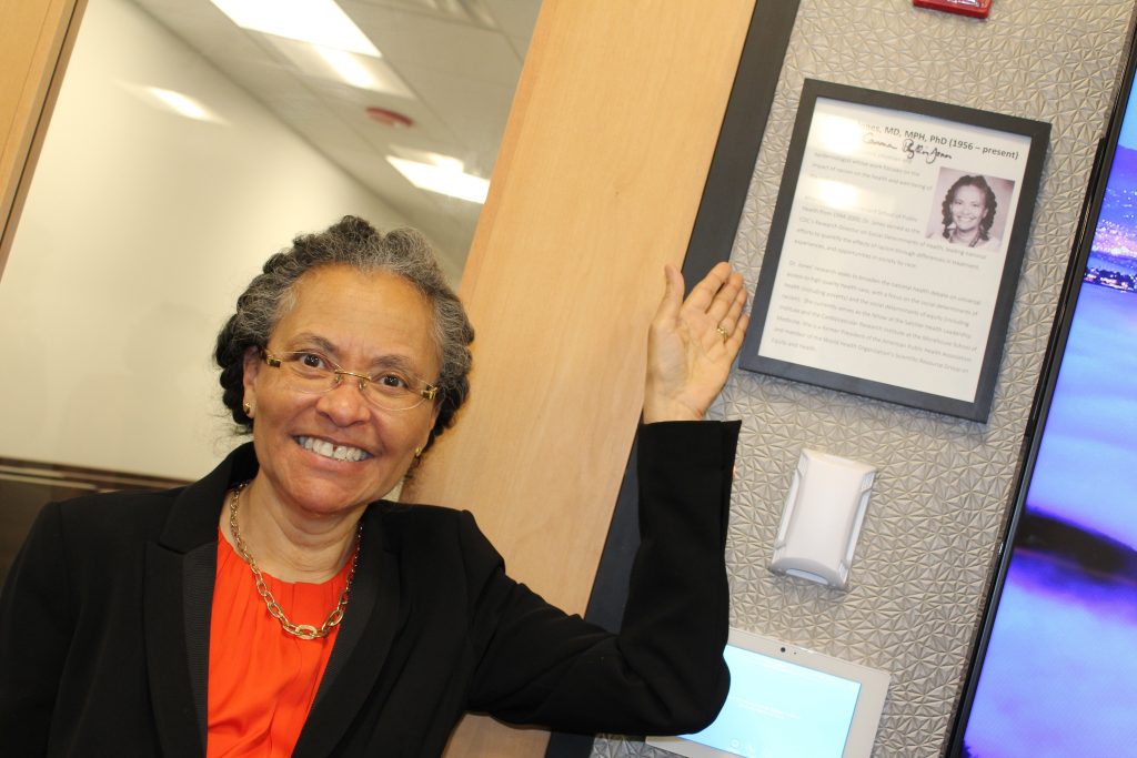 Dr. Camara Phyllis Jones posing with a framed photo of herself at HRiA headquarters