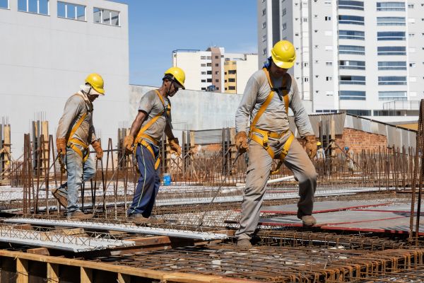 Three construction workers moving materials at an outdoor construction site