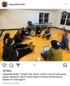 Screenshot of Instagram post by "nayouthcenter." Photo of young people sitting on the floor in a circle with HRiA facilitator. Caption: "tonight the senior youth council had some guest speakers talk to them about mental and physical health for teenagers!" Dated February 8, 2023.