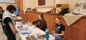 Two people tabling at an event, one smiling at the camera