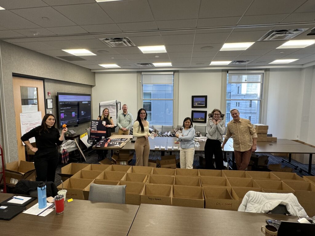 A group of people in a conference room organizing gambling disorder screening materials into many rows of cardboard boxes