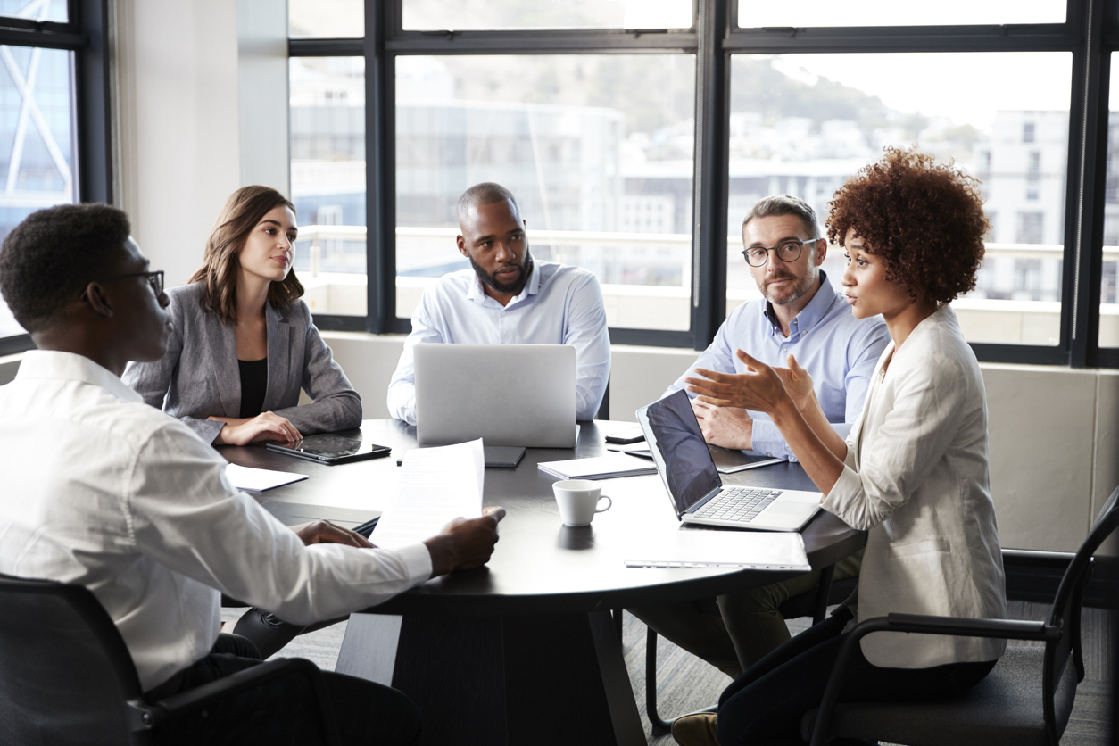 professional people gathered around a table with laptops and paper